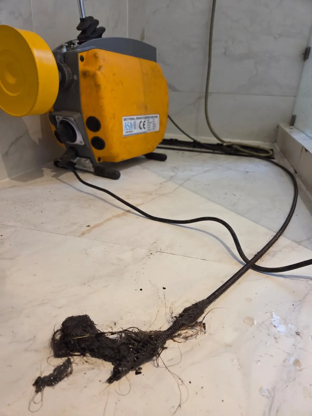 Sonda eléctrica con pelos y residuos retirados de una cañería tapada en Santiago